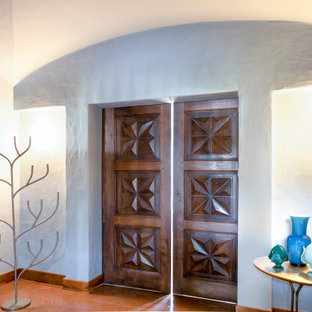 Modelo de distribuidor abovedado, moderno, grande, con paredes verdes, suelo de baldosas de terracota, puerta simple, puerta de madera en tonos medios y suelo naranja