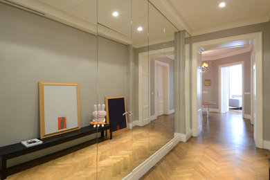 Esempio di un ingresso o corridoio minimal con pareti grigie e parquet chiaro