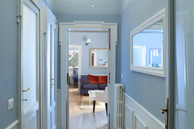 Modelo de hall actual de tamaño medio con paredes azules, suelo de madera clara, puerta simple, puerta de madera oscura y suelo beige