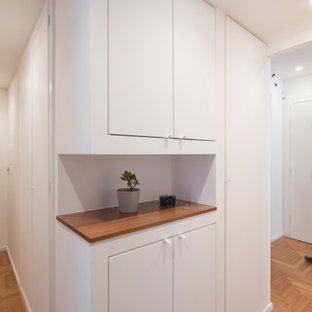 Exempel på en mellanstor modern hall, med vita väggar, ljust trägolv och brunt golv
