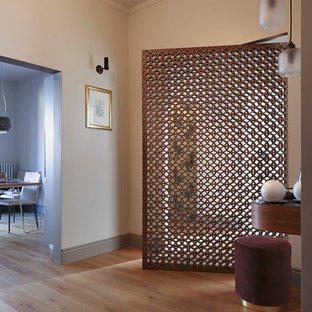 Esempio di un ingresso contemporaneo con pareti beige, parquet chiaro, una porta singola, una porta in metallo e pavimento marrone