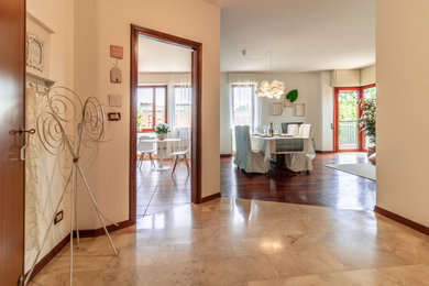 他の地域にある低価格の中くらいなモダンスタイルのおしゃれな玄関ロビー (白い壁、大理石の床、木目調のドア、ベージュの床) の写真
