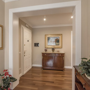 Imagen de distribuidor tradicional con paredes beige, suelo de madera en tonos medios, puerta simple y puerta blanca