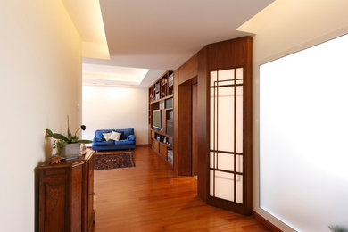 Immagine di un ingresso design con pareti bianche, pavimento in legno massello medio e pavimento marrone