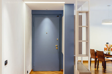 Idee per un corridoio minimal con pavimento in legno massello medio e una porta blu