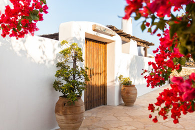 他の地域にある地中海スタイルのおしゃれな玄関ドア (白い壁、木目調のドア) の写真