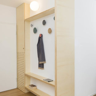 Foto di un ingresso nordico con pareti bianche, pavimento in legno massello medio, una porta singola, una porta bianca e pavimento marrone