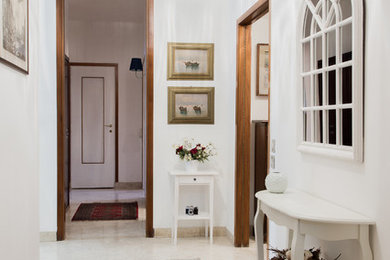 Esempio di un ingresso tradizionale di medie dimensioni con pareti bianche, pavimento in marmo e una porta in legno bruno