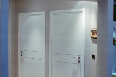 Ejemplo de hall contemporáneo de tamaño medio con paredes grises, suelo de madera clara, puerta simple y puerta gris