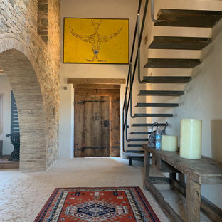 Esempio di un ampio corridoio mediterraneo con pareti beige, una porta singola, una porta in legno bruno, pavimento beige e pavimento in pietra calcarea