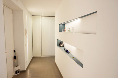 Immagine di un piccolo ingresso design con pareti bianche, pavimento in gres porcellanato, una porta a due ante, una porta bianca e pavimento grigio