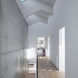Ispirazione per un grande ingresso o corridoio minimalista con pareti bianche, pavimento in legno massello medio e pavimento marrone