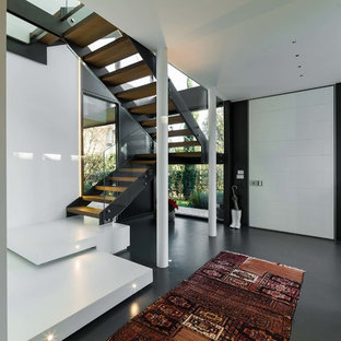 Esempio di un ingresso design con pavimento in cemento, una porta bianca, pareti bianche e pavimento grigio