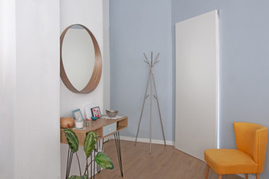 Ejemplo de distribuidor actual con paredes azules, suelo laminado, puerta corredera, puerta blanca y suelo beige