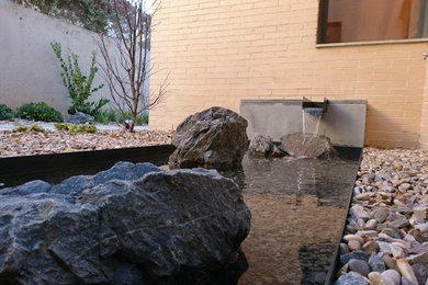 Imagen de jardín actual en patio lateral con fuente, exposición reducida al sol y gravilla
