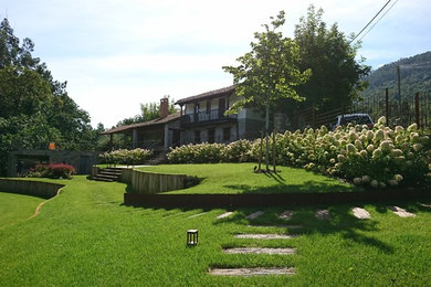 Foto de jardín ecléctico grande en verano con muro de contención y exposición parcial al sol