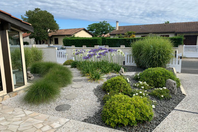 Ejemplo de jardín contemporáneo grande en patio delantero con parterre de flores, exposición total al sol y gravilla