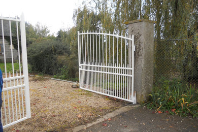 Aménagement d'un jardin sur cour classique de taille moyenne avec un portail et une clôture en métal.