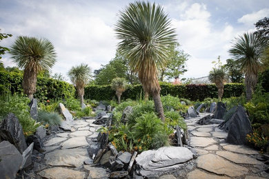 Cette image montre un grand jardin arrière design au printemps avec des pavés en pierre naturelle et une exposition partiellement ombragée.