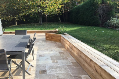 This is an example of a medium sized contemporary front full sun garden for winter in Paris with a retaining wall, decking and a metal fence.