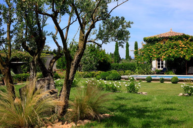 Exempel på en mycket stor klassisk trädgård i full sol på våren, med en fontän
