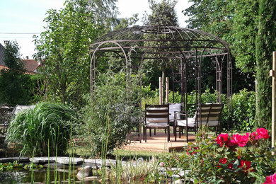 Exemple d'un jardin à la française arrière nature de taille moyenne avec un bassin, une exposition ensoleillée et une terrasse en bois.