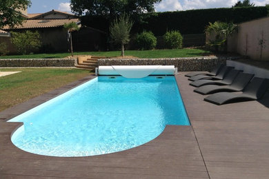 Cette image montre une grande piscine arrière design sur mesure avec une terrasse en bois.