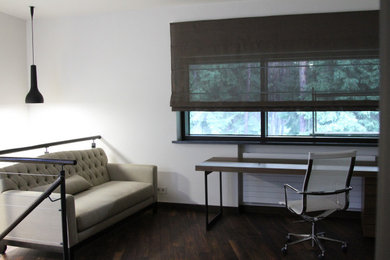 Стильный дизайн: рабочее место в современном стиле с белыми стенами, темным паркетным полом и отдельно стоящим рабочим столом - последний тренд