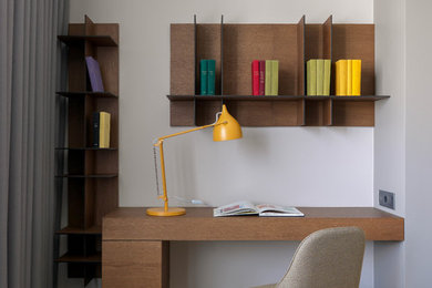 Imagen de despacho actual pequeño con paredes grises, suelo de madera en tonos medios, escritorio empotrado y suelo gris