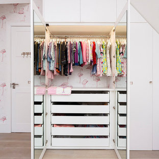 Photo of a contemporary kids' bedroom for girls in London with light hardwood flooring.