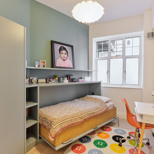 Photo of a medium sized contemporary children’s room for boys in London with blue walls, light hardwood flooring and beige floors.