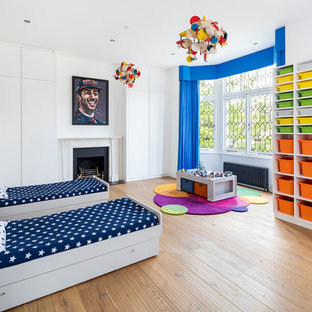 Inspiration for a large contemporary children’s room in London with white walls, light hardwood flooring and beige floors.