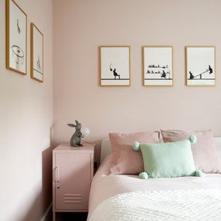 Photo of a contemporary kids' bedroom for girls in London with pink walls, carpet and grey floors.