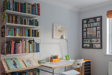 Ejemplo de habitación infantil unisex actual con escritorio, paredes grises, suelo de madera pintada y suelo gris