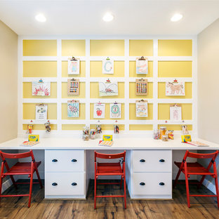 Foto de habitación infantil unisex de 4 a 10 años, tradicional renovada, de tamaño medio, con paredes amarillas, suelo de madera en tonos medios y escritorio