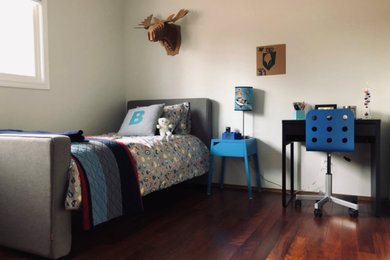 Medium sized contemporary children’s room for boys in Calgary with white walls, dark hardwood flooring and brown floors.