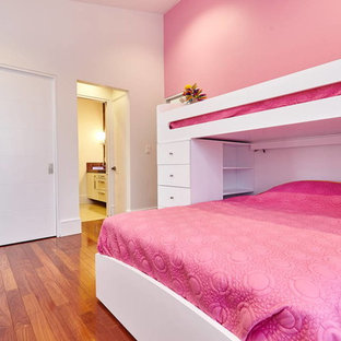 Esempio di una grande cameretta per bambini da 4 a 10 anni moderna con pareti rosa e pavimento in legno massello medio
