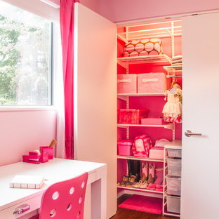 Immagine di una cameretta per bambini da 4 a 10 anni moderna di medie dimensioni con pareti rosa e parquet scuro