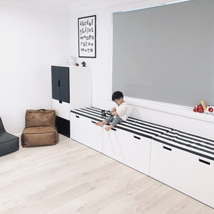 Idee per una cameretta per bambini da 1 a 3 anni moderna di medie dimensioni con pareti bianche, pavimento in laminato e pavimento beige