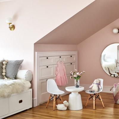 Large transitional girl medium tone wood floor and brown floor kids' room photo in Los Angeles with pink walls