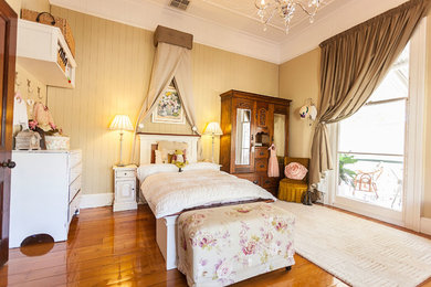 Diseño de dormitorio infantil de 4 a 10 años tradicional grande con suelo de madera en tonos medios y paredes amarillas