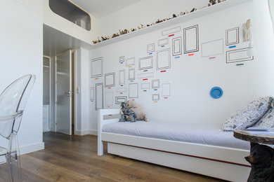 Cette image montre une chambre d'enfant de 4 à 10 ans minimaliste de taille moyenne avec un mur blanc et un sol en bois brun.