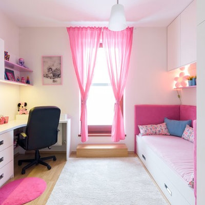 Example of a trendy girl light wood floor kids' room design with white walls