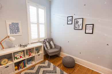 Cette image montre une chambre d'enfant de 1 à 3 ans minimaliste de taille moyenne avec un mur bleu et un sol en bois brun.