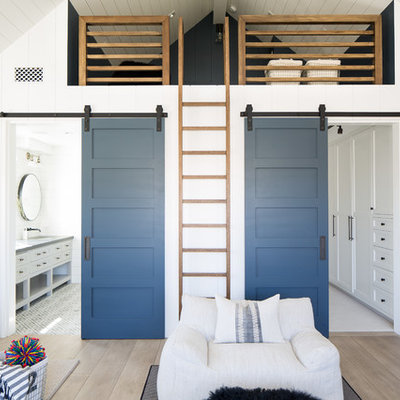 Example of a beach style gender-neutral medium tone wood floor and brown floor kids' bedroom design in Orange County with white walls