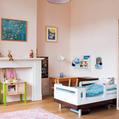 Example of a large eclectic girl medium tone wood floor kids' room design in Amsterdam with pink walls