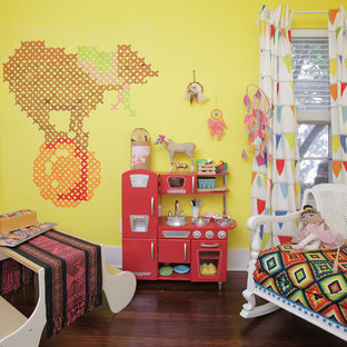 Immagine di una cameretta per bambini da 1 a 3 anni eclettica con pareti gialle e parquet scuro