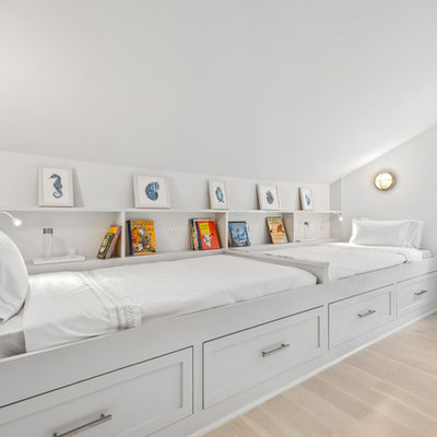 Example of a beach style gender-neutral light wood floor and beige floor kids' room design in New York with white walls