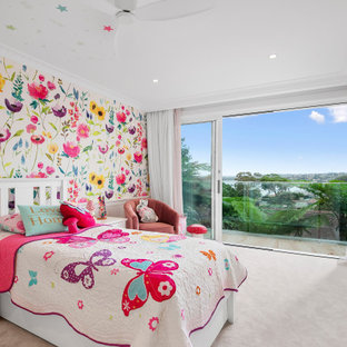 Photo of a large beach style kids' bedroom for kids 4-10 years old and girls in Sydney with multi-coloured walls, carpet, pink floor and wallpaper.