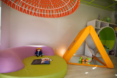 Example of a large minimalist gender-neutral light wood floor kids' room design in Omaha with white walls